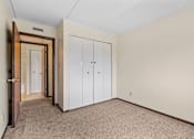 Thumbnail 18 of 29 - a bedroom with closet doors and carpeting and a door to a closet