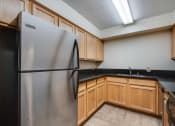 Thumbnail 7 of 13 - a kitchen with a stainless steel refrigerator and wooden cabinets
