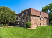Thumbnail 6 of 19 - a large brick house with a green lawn and trees