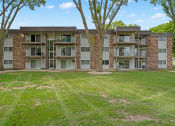 Thumbnail 6 of 20 - an apartment building with green grass and trees in front of it