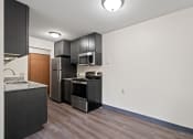 Thumbnail 11 of 20 - a kitchen with black appliances and white walls and wood flooring