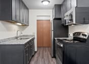 Thumbnail 10 of 20 - a kitchen with black cabinets and a stove and a refrigerator