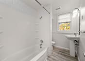 Thumbnail 9 of 10 - A white bathroom with a tub, sink, and toilet.