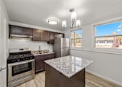 Thumbnail 1 of 10 - A kitchen with a granite counter top and stainless steel appliances.