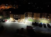 Thumbnail 26 of 26 - a parking lot at night with cars parked in front of a building