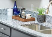 Thumbnail 9 of 80 - A kitchen counter with a sink, a coffee maker, and a potted plant.at Addison at Sutherland, Knoxville, 37909  