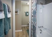 Thumbnail 32 of 80 - A bathroom with a white tub and a shower with a blue and white curtain.at Addison at Sutherland, Tennessee  