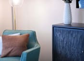 Thumbnail 47 of 80 - A blue chair with a brown pillow sits next to a blue cabinet with a white vase on top.at Addison at Sutherland, Tennessee  