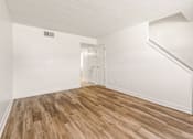 Thumbnail 4 of 15 - A room with wooden flooring and white walls.