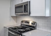 Thumbnail 12 of 15 - A modern kitchen with a stove top oven and microwave above it.