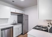 Thumbnail 11 of 15 - A kitchen with white cabinets and a stainless steel refrigerator.