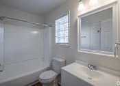 Thumbnail 13 of 15 - A white bathroom with a toilet, sink, and bathtub.