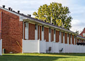 Thumbnail 9 of 16 - A white picket fence surrounds a red brick building.