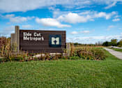 Thumbnail 14 of 16 - A sign for Side Cut Metropark stands in a grassy field.