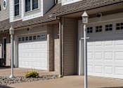 Thumbnail 4 of 14 - A house with two white garage doors and a lamp post in front.