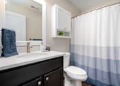 Thumbnail 12 of 23 - A white sink with a blue towel and a white toilet in a bathroom.