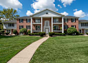 Thumbnail 2 of 10 - A large brick building with a white door and windows.