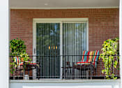 Thumbnail 7 of 10 - A patio with a chair and a table with a striped cushion.