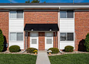 Thumbnail 2 of 16 - A brick building with a white door and windows.