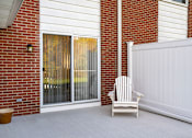 Thumbnail 8 of 16 - A white chair is placed in front of a white fence and a glass door.