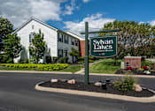 Thumbnail 1 of 20 - A sign for Sylvan Lakes Apartment Homes stands in front of a building.