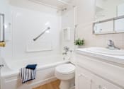 Thumbnail 6 of 15 - A white bathroom with a towel hanging on the tub.