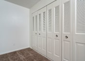 Thumbnail 11 of 20 - Closet with white doors and brown carpet.