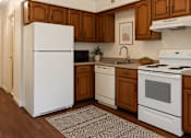 Thumbnail 5 of 10 - A white refrigerator stands in a kitchen with wooden cabinets and white appliances.