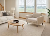 Thumbnail 9 of 14 - A living room with a white sofa, a white armchair, a wooden coffee table, and a large window with white curtains.