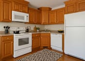 Thumbnail 5 of 14 - A kitchen with white appliances and wooden cabinets.