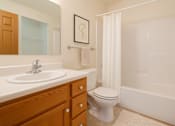 Thumbnail 7 of 14 - A white toilet sits next to a sink in a bathroom.