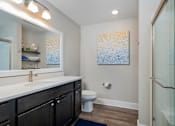 Thumbnail 14 of 23 - A bathroom with a white counter top and a painting on the wall.