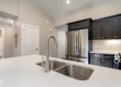 Thumbnail 9 of 23 - A modern kitchen with a stainless steel sink and refrigerator.