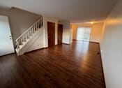 Thumbnail 5 of 16 - A room with wooden floors and a staircase.