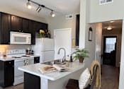Thumbnail 8 of 20 - A kitchen with black cabinets and white appliances.
