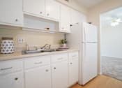 Thumbnail 5 of 15 - A kitchen with white cabinets and a white refrigerator.