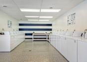 Thumbnail 15 of 20 - A laundromat with rows of washers and dryers.