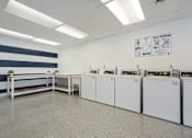 Thumbnail 16 of 20 - A laundry room with washers and dryers lined up on the wall.