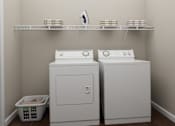 Thumbnail 18 of 23 - Two white front loading washing machines in a laundry room.