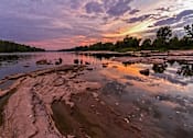 Thumbnail 15 of 16 - A serene landscape with a river, rocks, and a sunset.