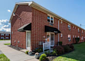Thumbnail 15 of 16 - A red brick building with a white door and a black awning.