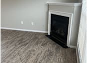 Thumbnail 16 of 20 - A fireplace with a white mantle and a black hearth sits in a room with wood flooring.