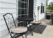 Thumbnail 17 of 20 - A black metal chair with a striped cushion sits on a patio.