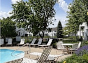 Thumbnail 6 of 20 - A poolside area with chairs and tables.