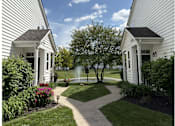 Thumbnail 4 of 20 - A white house with a black roof and a small garden in front.