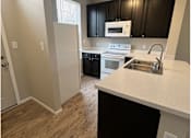 Thumbnail 15 of 20 - A kitchen with black cabinets and a white counter.