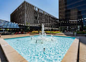 Thumbnail 26 of 34 - A fountain in the middle of a pool surrounded by buildings.