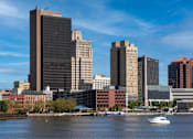 Thumbnail 27 of 34 - A cityscape with a boat in the water.