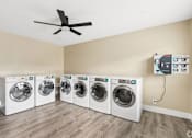 Thumbnail 14 of 17 - A room with a white ceiling fan and four washing machines.