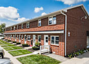 Thumbnail 15 of 17 - A red brick house with a white door and windows.
